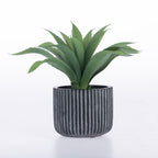 An artificial green succulent plant with spiky leaves in a dark gray ribbed cylindrical pot, set against a plain white background.