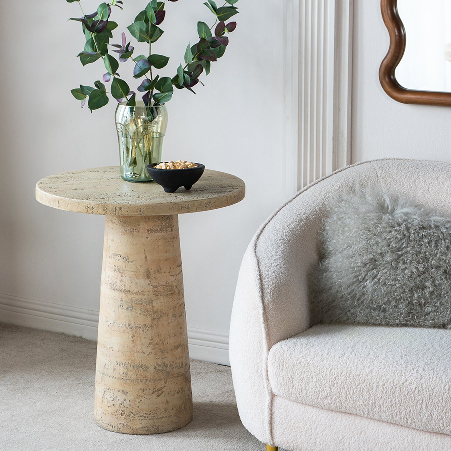 Design Republique Natural Cement Round Side Table styled beside a bouclé armchair with a green glass vase and decorative bowl on the tabletop.