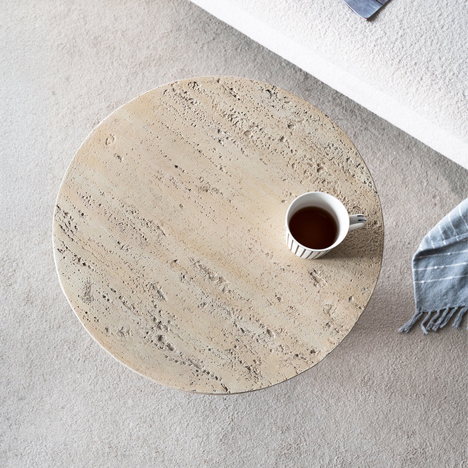 Top-down view of the Design Republique Natural Cement Round Side Table styled beside a sofa with a striped mug on the textured tabletop.