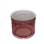 A contemporary round coffee table featuring a clear glass top and a sculptural red perforated metal base with an industrial-inspired design.