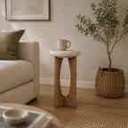 Natural stone and solid wood side table styled beside a neutral sofa in a contemporary living room with a ceramic mug, woven basket planter, and warm natural décor.