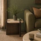 Carter Marble Side Table styled beside an olive green sofa, featuring a natural travertine marble top with a dark timber base, decorated with a ceramic vase and mug in a warm contemporary living room.
