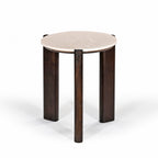Front angled view of the round side table with a cream marble top and sculptural dark brown timber legs on a white background.