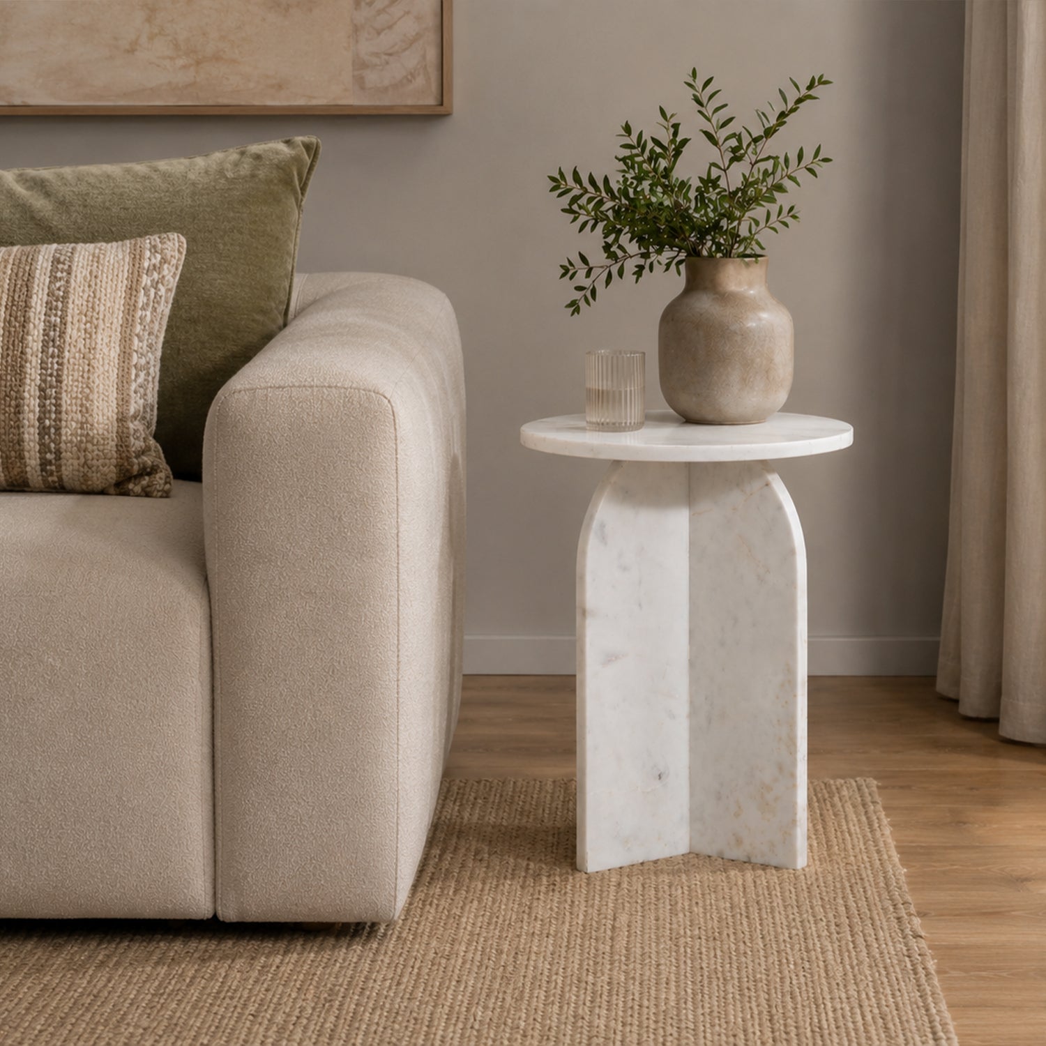 Styled living room scene featuring the white marble side table beside a cream sofa, styled with a ceramic vase and greenery to showcase its elegant contemporary design.