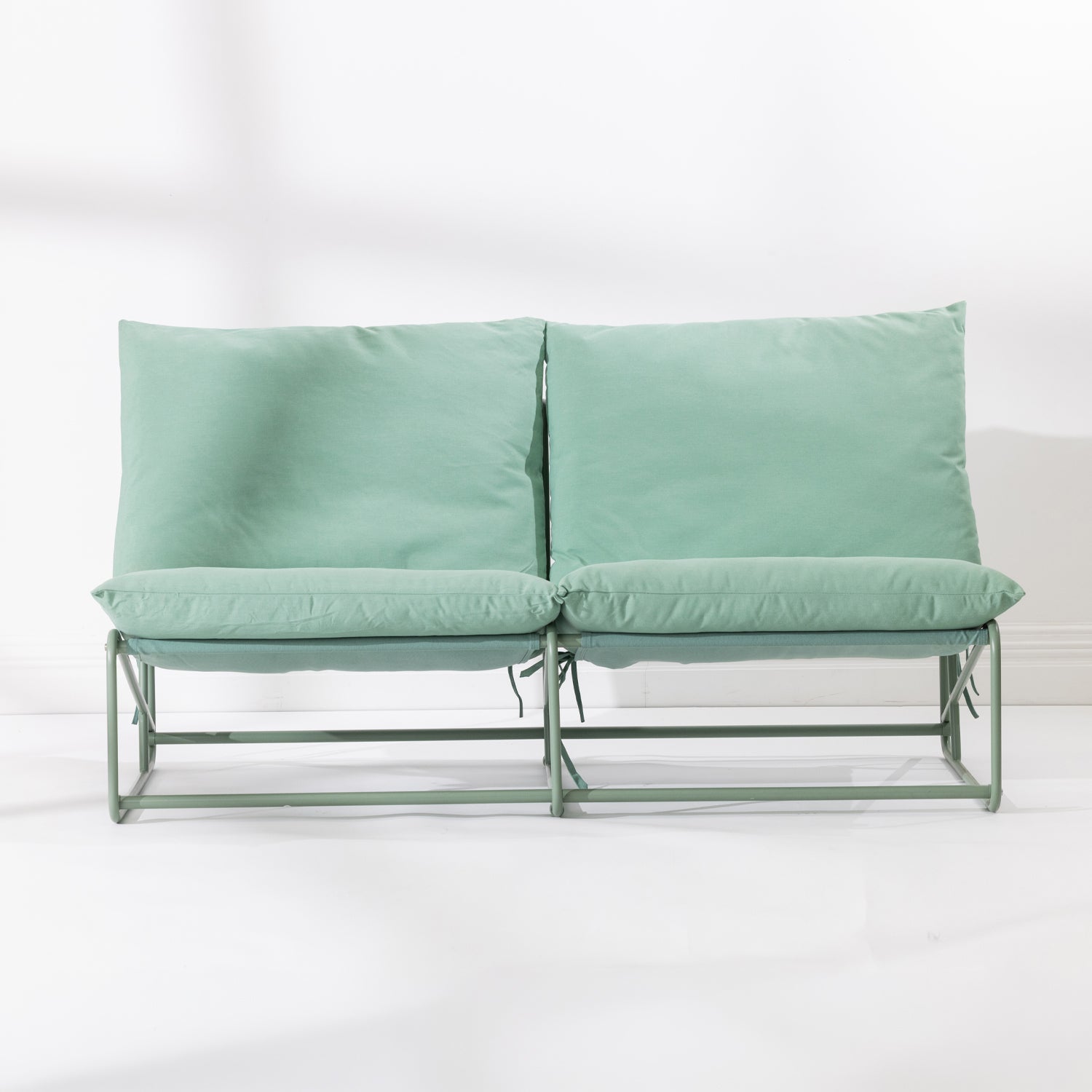 A two-seat cushioned outdoor sofa with a slim green metal frame and green cushions, set against a clean white background.