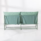 The back of a two-seat cushioned outdoor sofa with a slim green metal frame and green cushions, set against a clean white background.