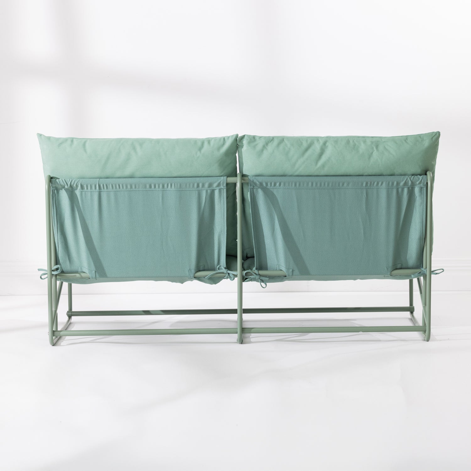 The back of a two-seat cushioned outdoor sofa with a slim green metal frame and green cushions, set against a clean white background.