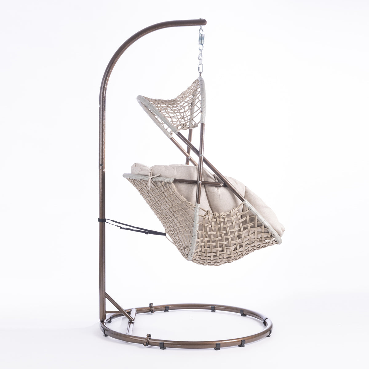 A hanging egg chair with a woven wicker body, beige cushions, and a dark metal stand, photographed in a bright white studio setting.