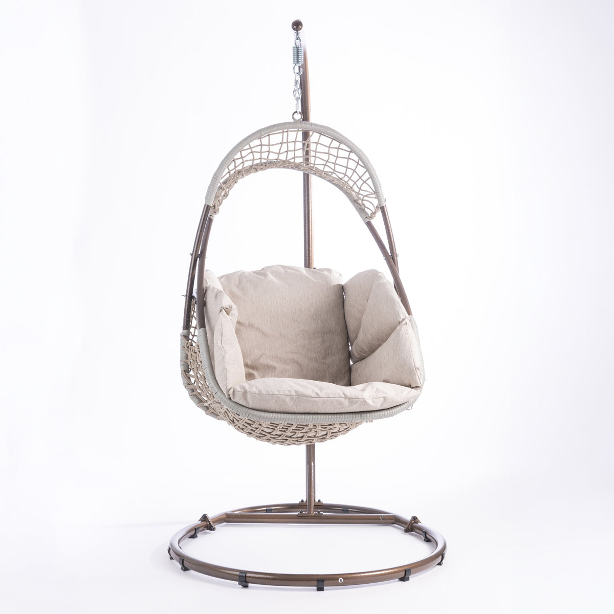 A hanging egg chair with a woven wicker body, beige cushions, and a dark metal stand, photographed in a bright white studio setting.