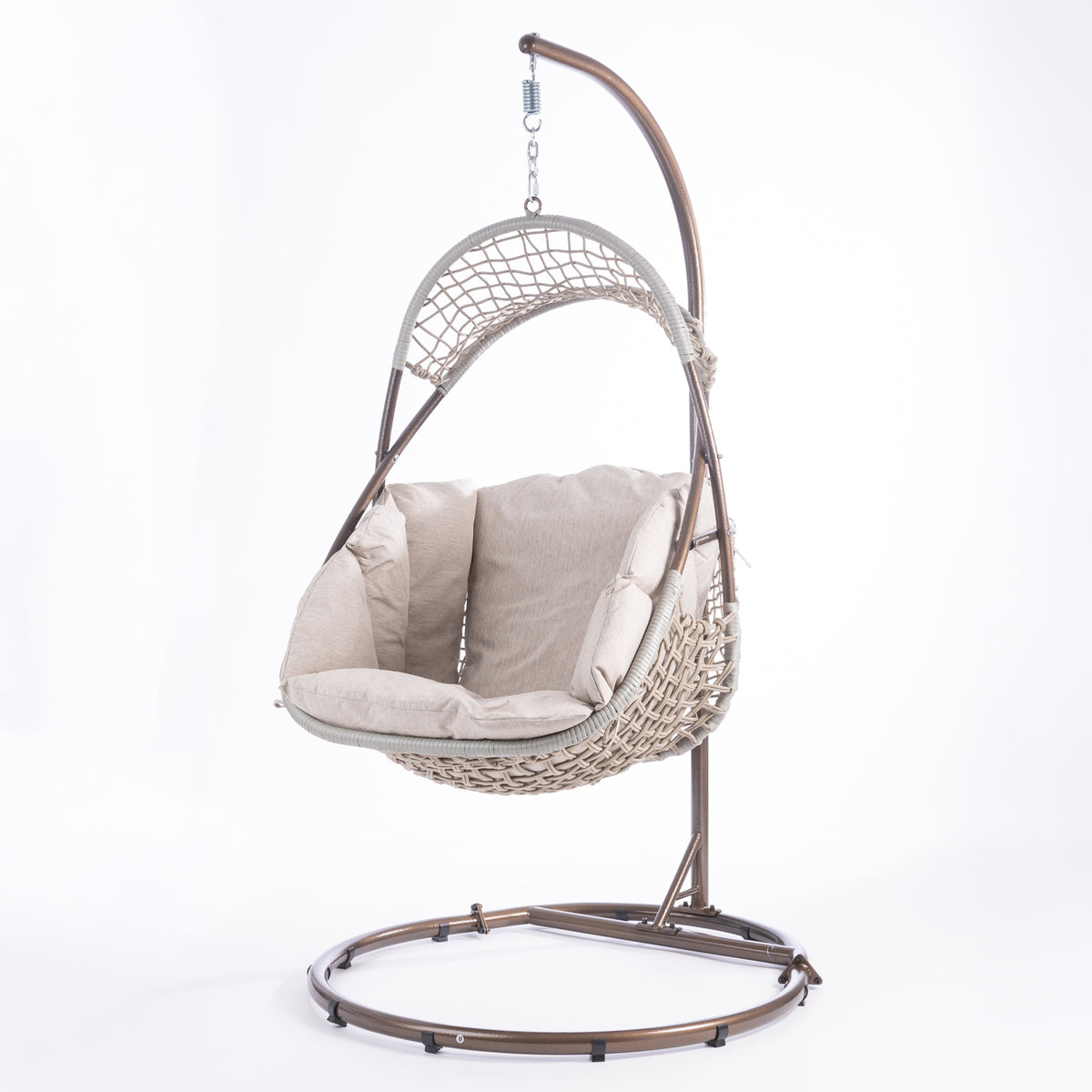 A hanging egg chair with a woven wicker body, beige cushions, and a dark metal stand, photographed in a bright white studio setting.