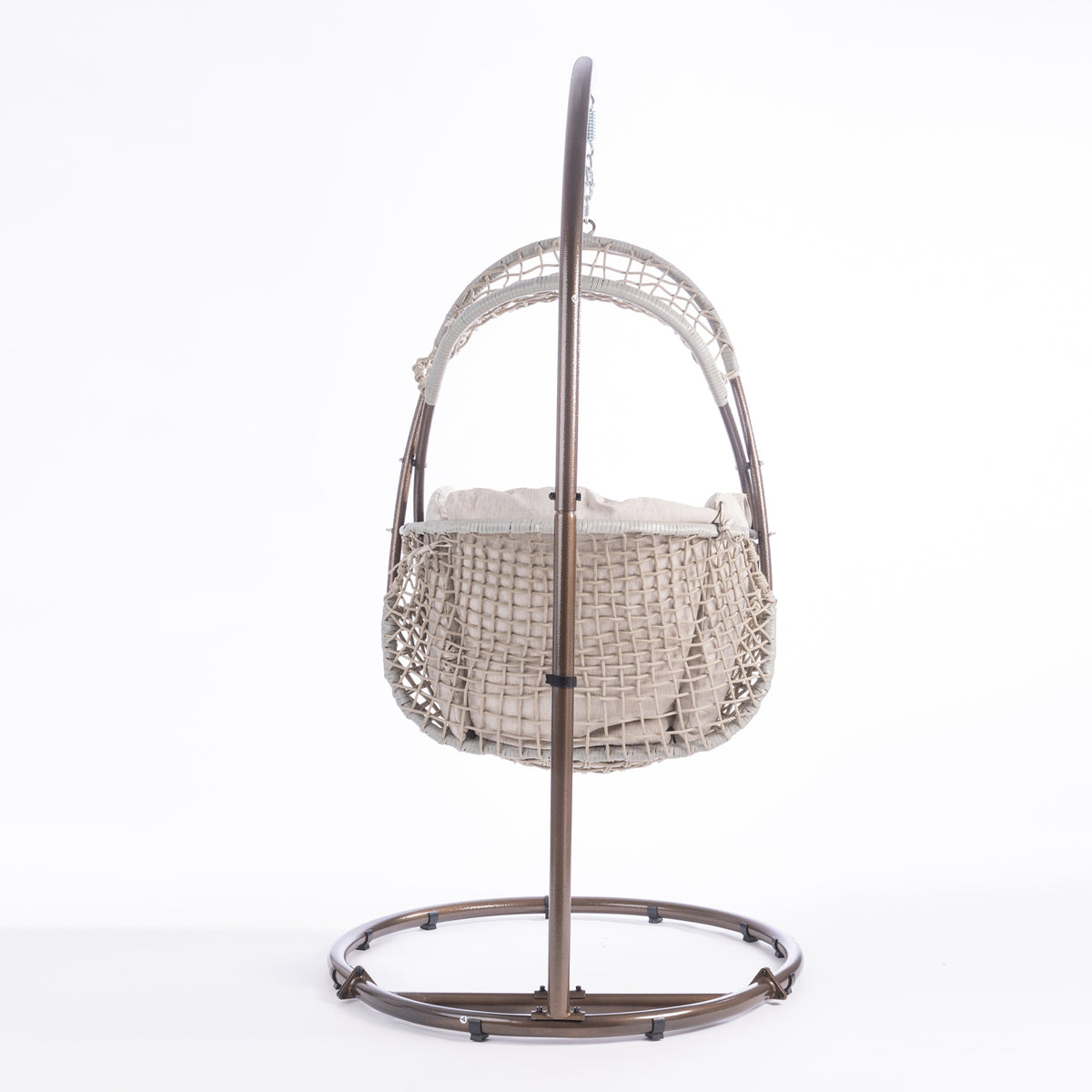 A hanging egg chair with a woven wicker body, beige cushions, and a dark metal stand, photographed in a bright white studio setting.