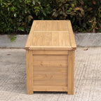 A rectangular wooden storage box made of light natural wood, photographed outdoors on a concrete surface with green foliage in the background.