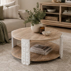 Round natural wood coffee table with a lower shelf and carved antique white legs featuring decorative floral detailing.