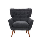 Charcoal upholstered armchair with a button-tufted wingback design, wide cushioned seat, angled armrests and tapered wooden legs.