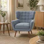 Grey-blue button-tufted accent armchair styled in a contemporary living room with natural wood furniture, neutral décor and soft natural lighting.