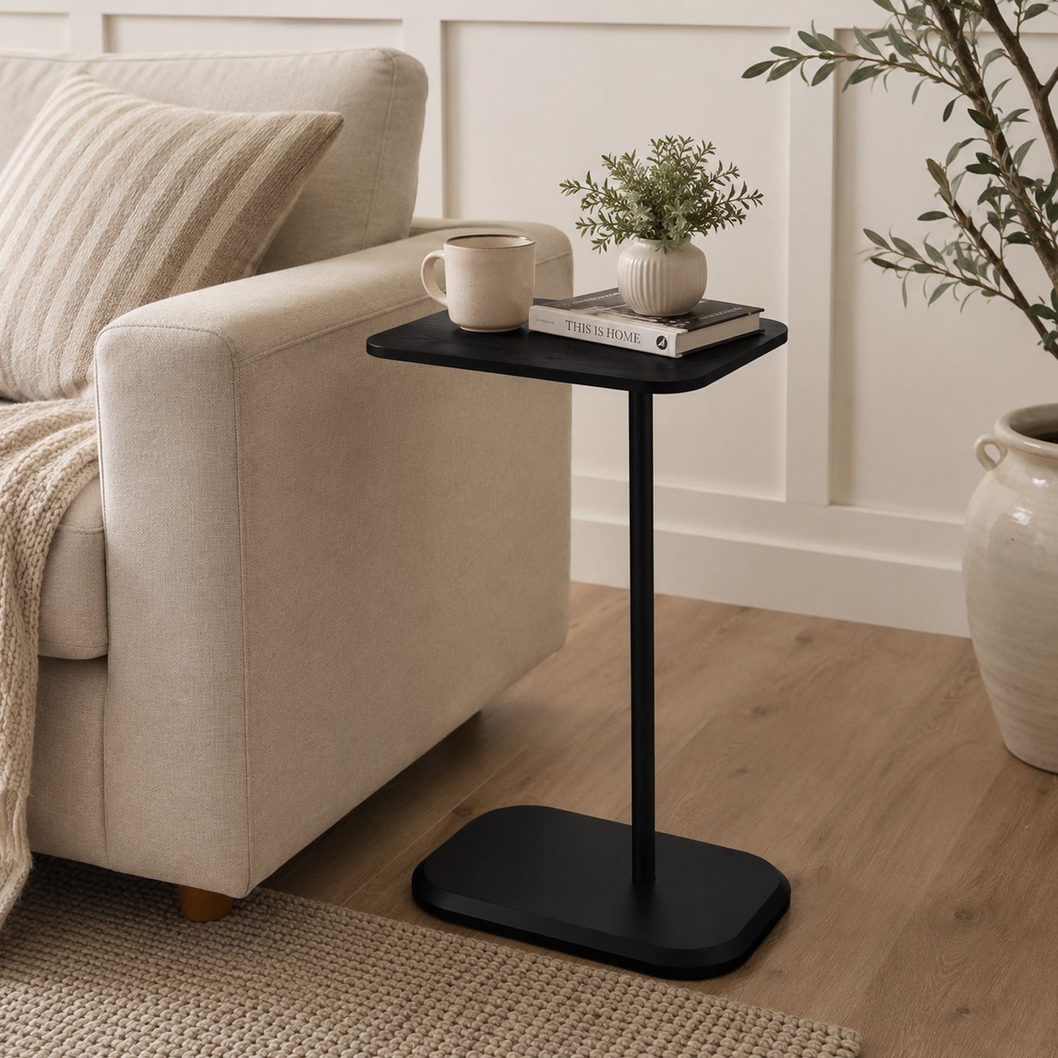 A sleek black side table styled with a coffee mug, book, and greenery complements a warm modern farmhouse living room with understated elegance and everyday functionality.