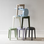 A collection of stackable stools in soft contemporary colours is arranged in an artistic display, highlighting their versatile, space-saving design and modern minimalist style.