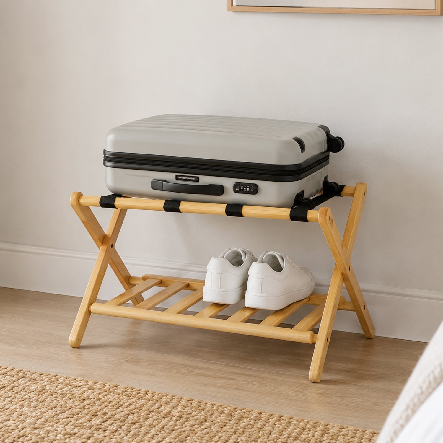 Home Co. Piper Bamboo Luggage Rack in natural bamboo styled in a bedroom with a suitcase on the upper straps and white shoes stored on the lower slatted shelf.