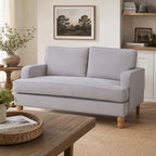 A timeless natural two-seater sofa with clean lines, generously cushioned seating and natural timber legs is styled in a warm, contemporary living room for a relaxed and inviting look.