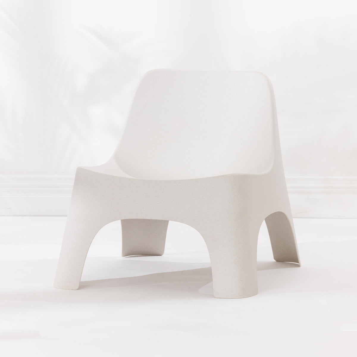 A modern moulded plastic chair in a cream colour.