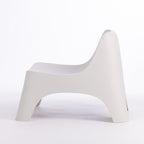 A modern moulded plastic chair in a cream colour.