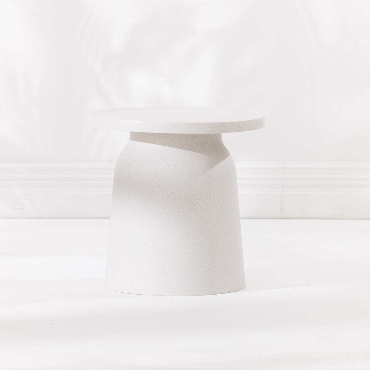 A minimalist, modern side table in a cream hue, photographed on a seamless white background.