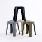Four stools in black, stormy grey, olive & cream, stacked together on a clean white studio background.