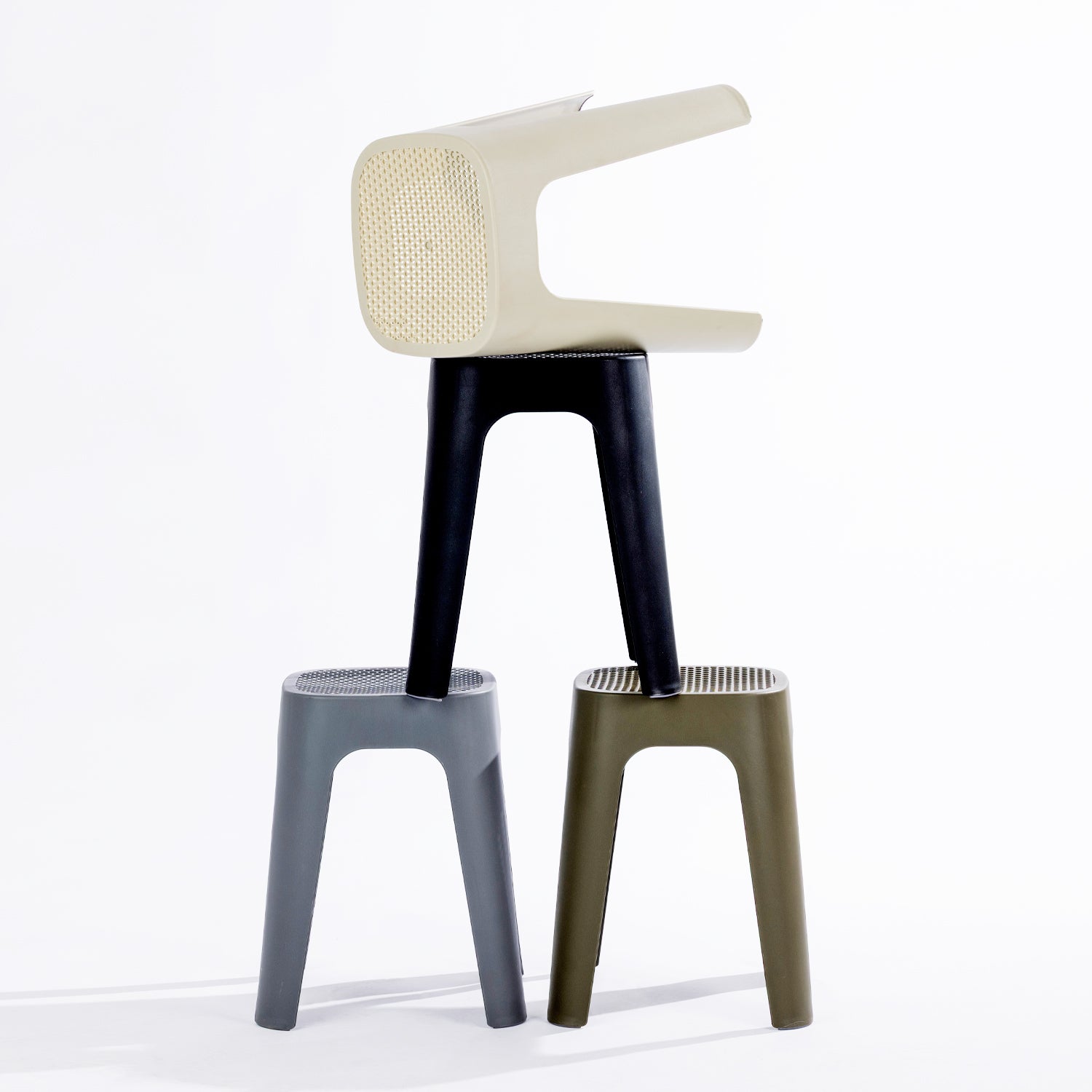 Four stools in black, stormy grey, olive & cream, stacked together on a clean white studio background.
