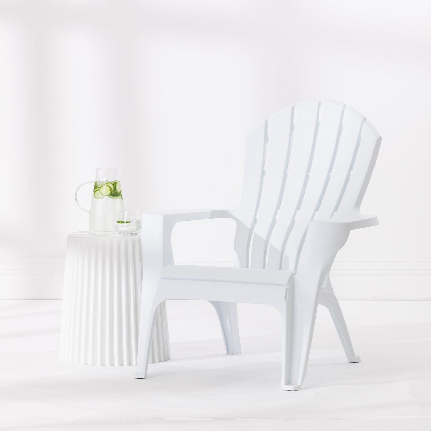 White Cape Cod chair styled beside a white side table with a glass jug and drinking glass against a bright white studio background.