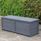 A charcoal wooden storage box, set outdoors on a concrete surface with green bushes in the background.