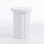 A white speckled side table with a fluted column base and a round top, shown on a seamless white background.