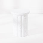 A white fluted pedestal side table with a speckled like finish, set against a clean white background.