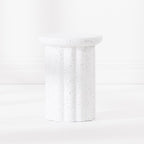A white fluted pedestal side table with a speckled like finish, set against a clean white background.