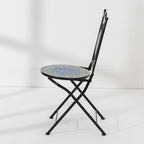 Side view of the Outsidings Blue Tile Mosaic Chair showing its folding black metal frame and circular mosaic seat.