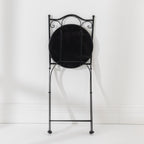 Rear view of the folded Outsidings Blue Tile Mosaic Chair showing the black metal frame and underside of the mosaic seat.