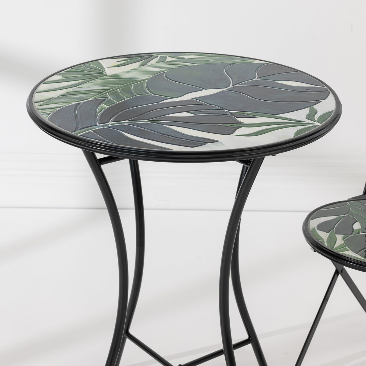 Close-up of the Outsidings Green Leaves Mosaic Table showing the detailed green leaf mosaic tabletop and black metal frame.