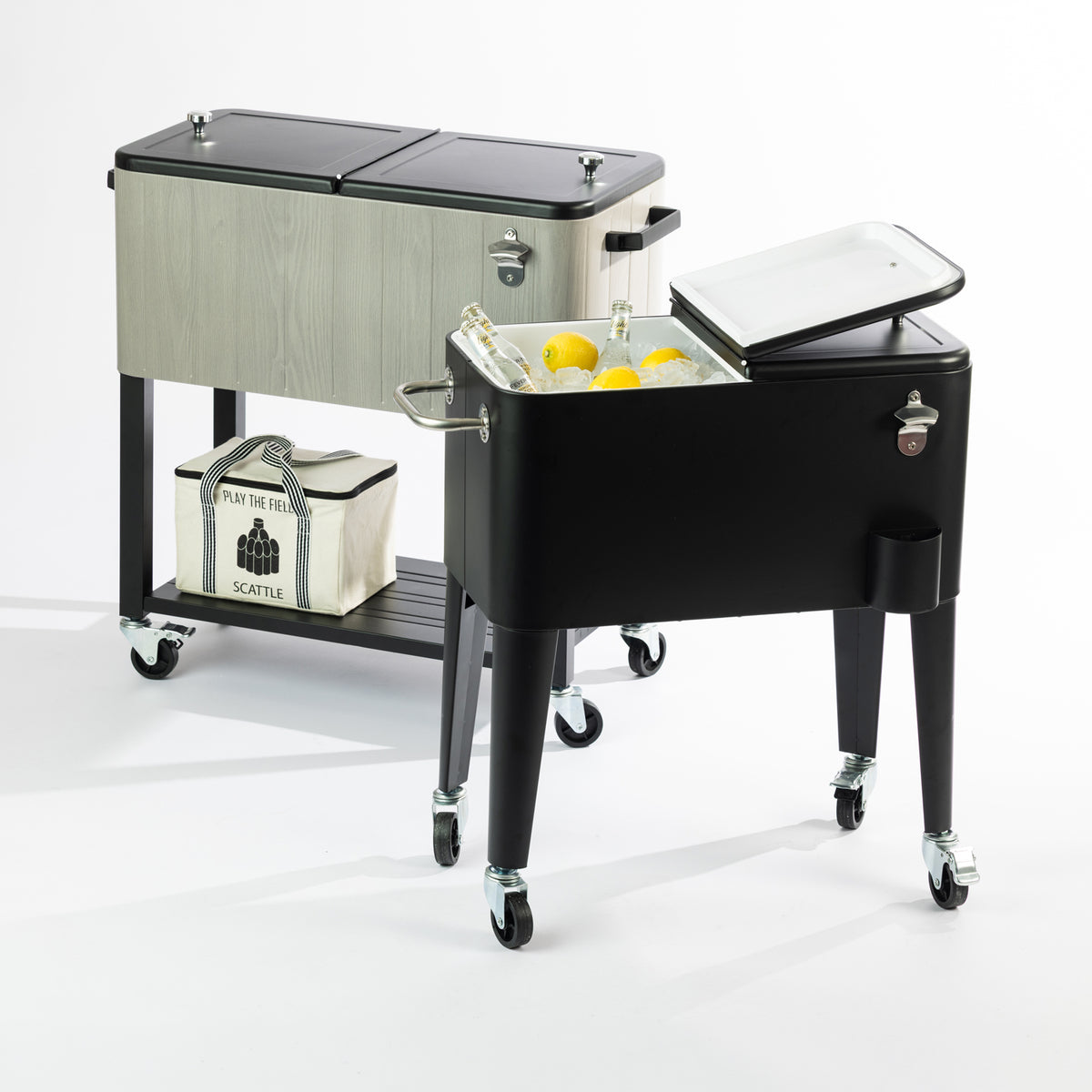 Outsidings Arctic Cooler Box Range featuring the Black 57L Cooler Box and Grey Wood Look 76L Cooler Box. Both feature split-lid designs, insulated interiors, built-in bottle openers, bottle cap catchers and caster wheels. The black cooler is displayed with ice, bottled drinks and lemons, while the grey wood-look cooler features a convenient lower storage shelf.
