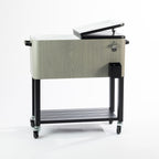 Grey wood-look 76L cooler box displayed with one lid open, revealing its spacious white insulated interior. Features a black metal frame, lower slatted storage shelf and caster wheels for convenient mobility.