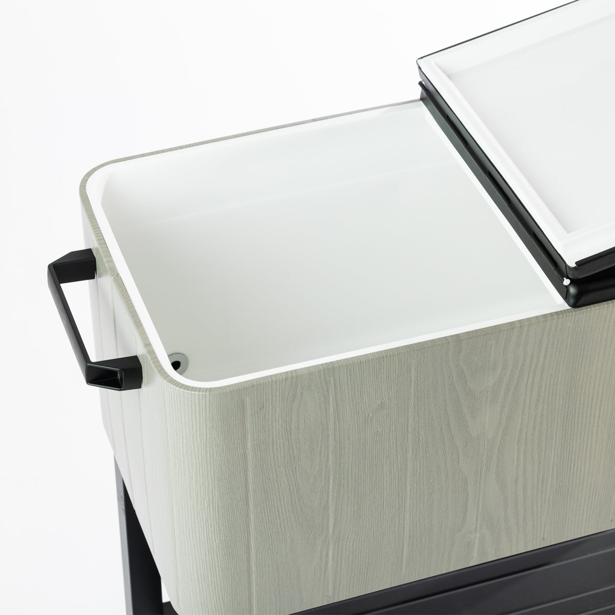 Close-up of the grey wood-look cooler box's large white insulated interior, showcasing the split-lid design and smooth interior surface with a visible drainage opening.