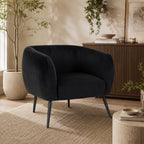 Design Republique Olivia Black Velvet Chair with a curved wraparound silhouette and black metal legs, styled in a contemporary living room with a textured rug, timber sideboard and indoor greenery.