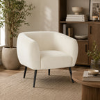 Design Republique Olivia Cream Velvet Chair with a curved wraparound silhouette, soft cream velvet upholstery and black metal legs, styled in a warm contemporary living room with timber furniture and natural décor.