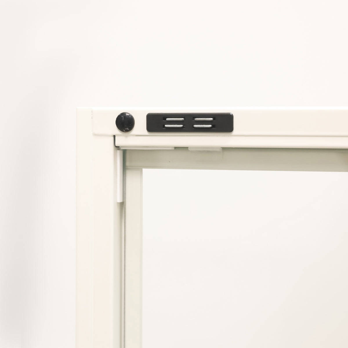 Close-up of the white shelving cabinet's glass door frame, highlighting the black magnetic door catch and fastening details.
