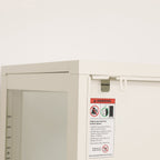 Close-up of the white shelving cabinet's rear corner, showing the furniture anti-tip bracket and safety warning label.