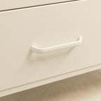 A close-up of a minimalist, curved drawer pull handle in a warm off-white finish mounted on a matching cream-colored drawer front.