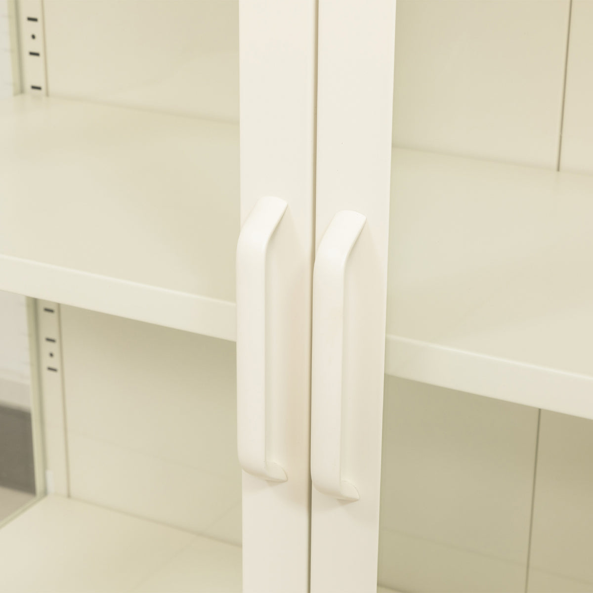 A close-up of a pair of white cabinet door handles.