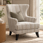 A striped wingback armchair in a neutral fabric, styled with a matching throw pillow in a bright, modern living room setting.