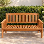 Outsidings Santos three-seater wooden bench displayed on a paved outdoor patio against a lush green hedge, highlighting its natural timber finish.