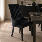 Design Republique Harvey Dining Chair in Black styled at a contemporary dining table, showcasing the button-tufted velvet upholstery, silver stud trim, and elegant high-back design.