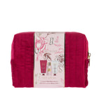 Grace & Gild Luxury Florals travel gift set presented in a rich berry-pink quilted cosmetic bag with gold zip detailing. A floral paper sleeve wraps around the bag and showcases the coordinating Rose & Berries body care products inside.