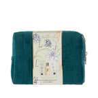 Grace & Gild Luxury Florals travel gift set presented in a deep teal quilted cosmetic bag with gold zip detailing. A pale green floral sleeve wraps around the bag, highlighting the Royal Lily & Vanilla body care range.